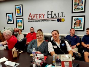 Man and Woman sitting at a table behind them is Avery Halls logo signage