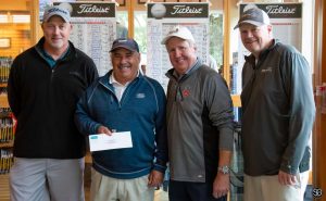 Group of 4 golfers, one man is holding an envelope