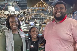 Three people standing inside a restaurant wearing name tags for an alumni event