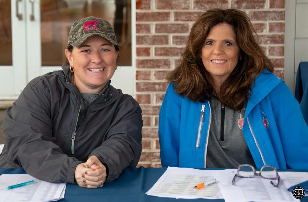 Two women sitting at a registration table at a golf tournament