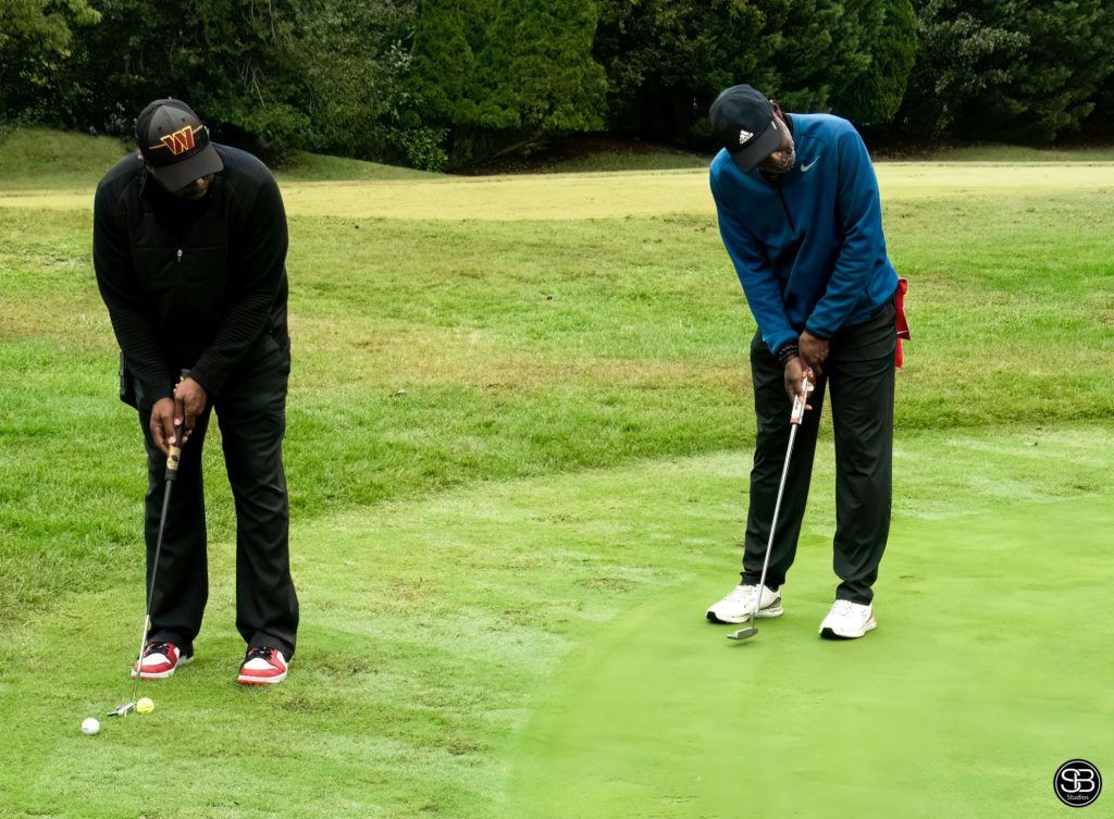 Two men putting golf balls on a golf green