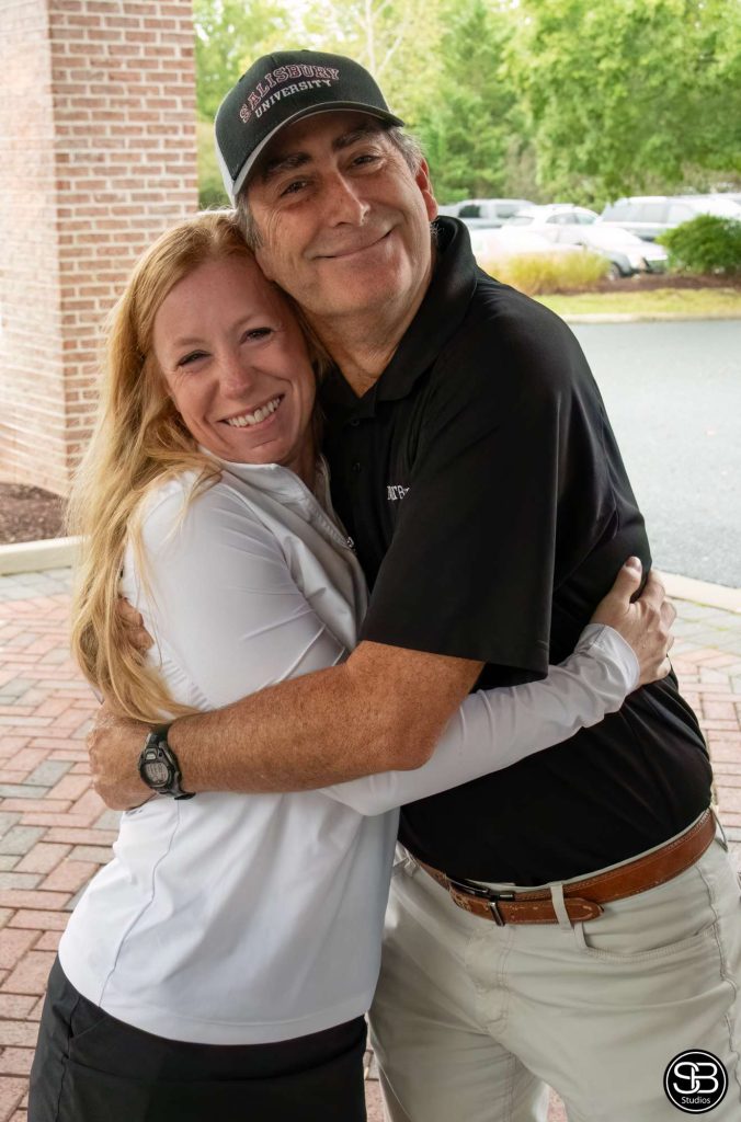Man in a black shirt hugging a woman in a white shirt