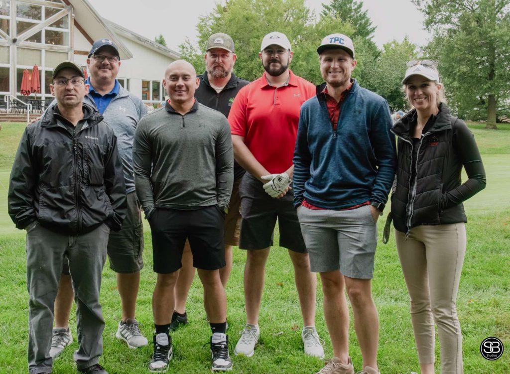 Group of 7 golfers posing for a picture on the golf course
