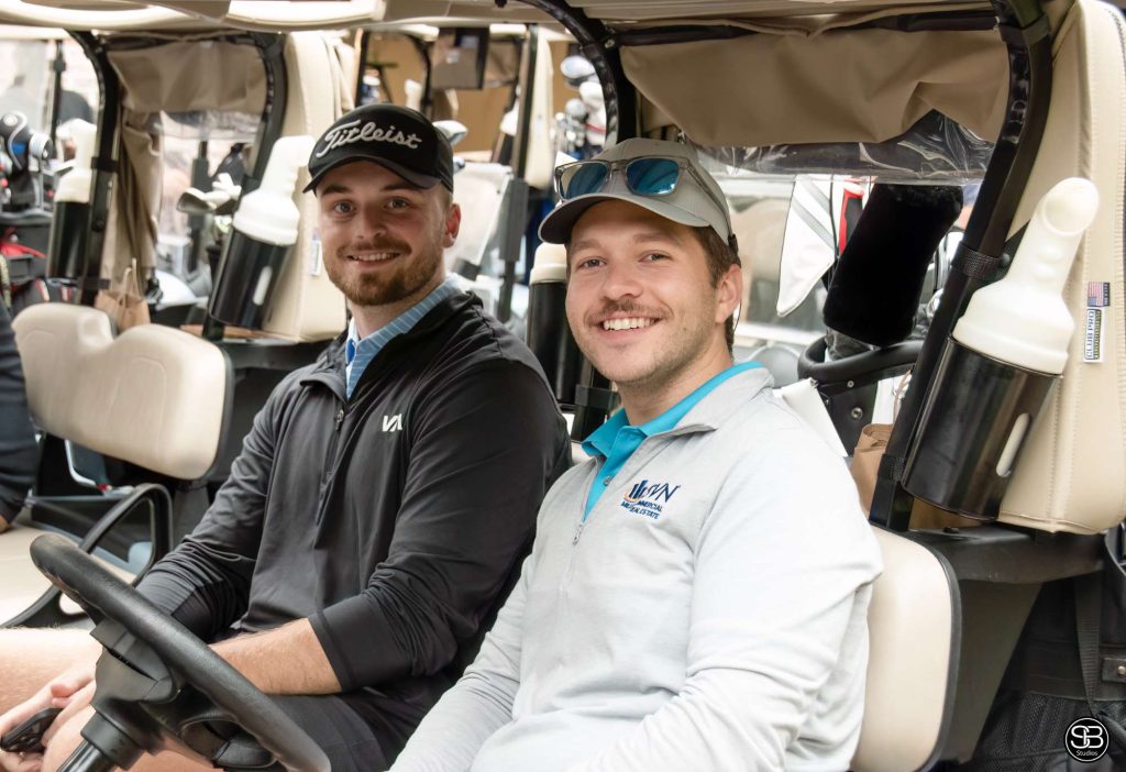 Two men sitting on a golf cart