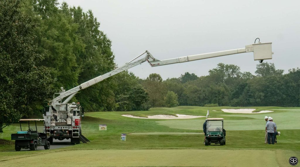 Golf cart on the course with a bucket truck extended above it