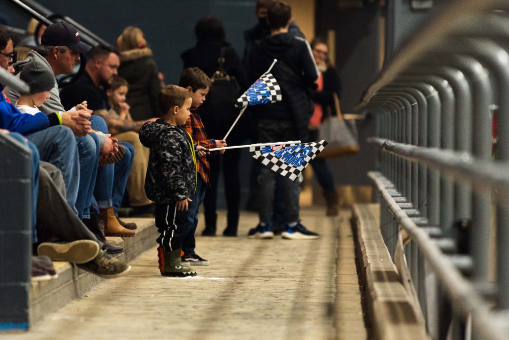 two little boys holding checkered flags in a stadium 