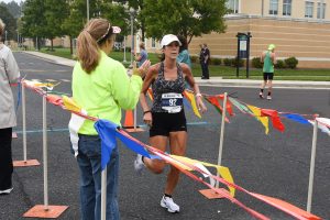 Young woman running through the finish line for a 5K race