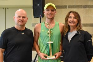 two men and a woman standing with a large gold trophy