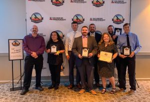 eight people dressed in business attire holding awards