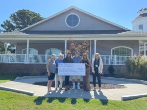 Group of people holding a large check on a beautiful sunny day