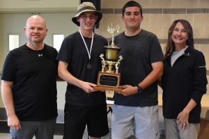 three men and a woman standing with a gold trophy