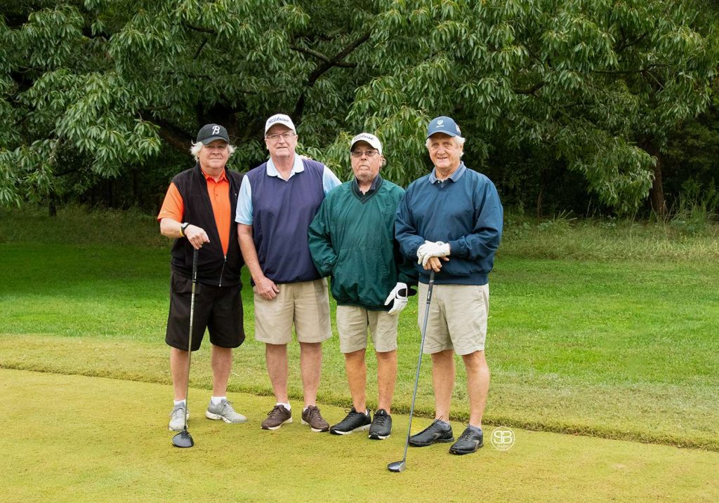 Golf Tournament Foursome standing on a golf course, two men holding golf clubs