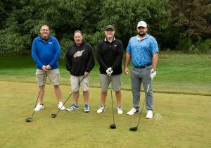 Golf Tournament Foursome standing on a golf course, four men holding golf clubs