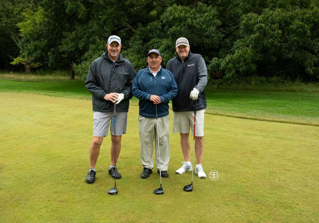 Golf Tournament with three men standing on a golf course