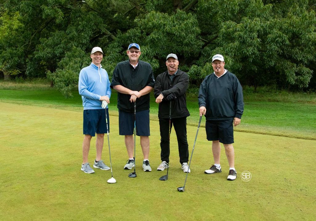 Golf Tournament Foursome of four men standing on a golf course Two men holding cigars in their mouths