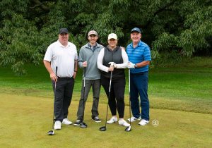 Golf Tournament Foursome of three men and one woman standing on a golf course