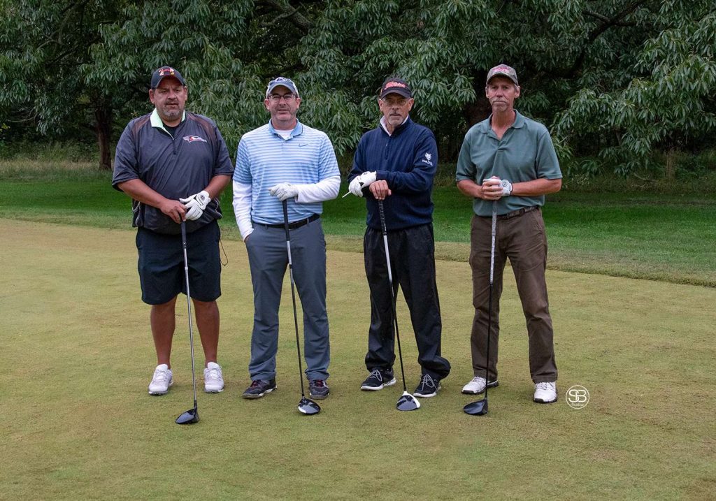 Golf Tournament Foursome of four men standing on a golf course