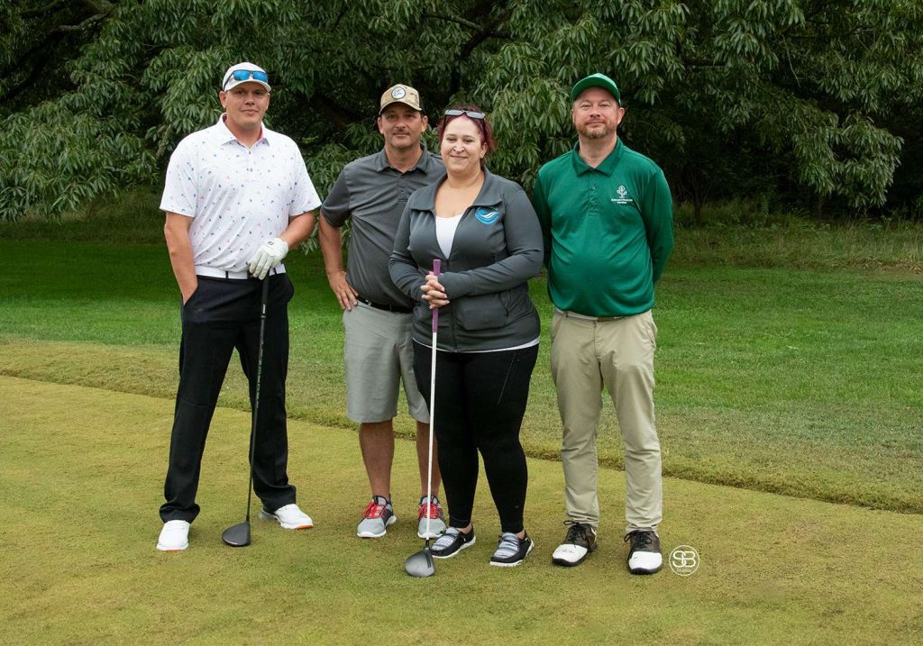 Golf Tournament Foursome of three men and a woman standing on a golf course