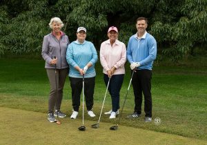 Golf Tournament Foursome of three women and one man standing on a golf course