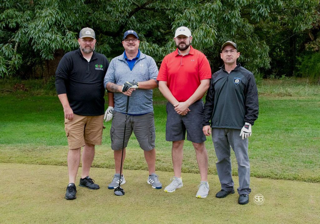 Golf Tournament Foursome of four men standing on a golf course