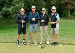 Golf Tournament Foursome of three men and a woman standing on a golf course