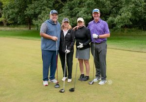 Golf Tournament Foursome of two women and two men standing on a golf course