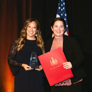 Two young women holding awards on stage