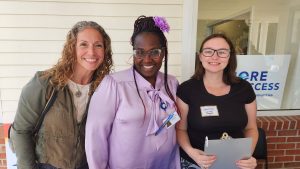 Three women smiling for the camera infront of Shore Legal Access building