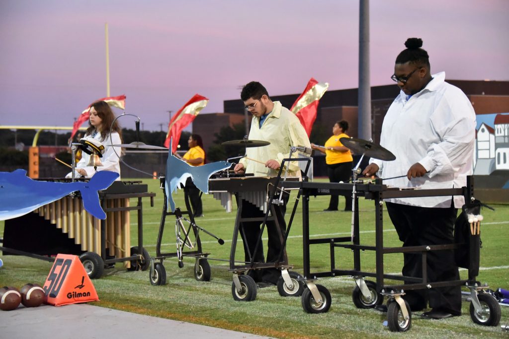 Marching band members playing during the sunset
