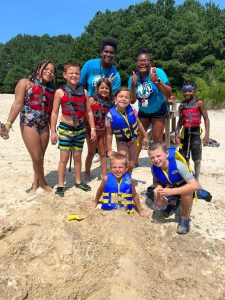 Large group of kids wearing life jackets while standing on the sand