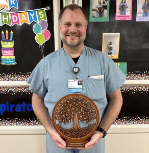 Respiratory Therapist from Tidal Health holding an award shaped like a tree