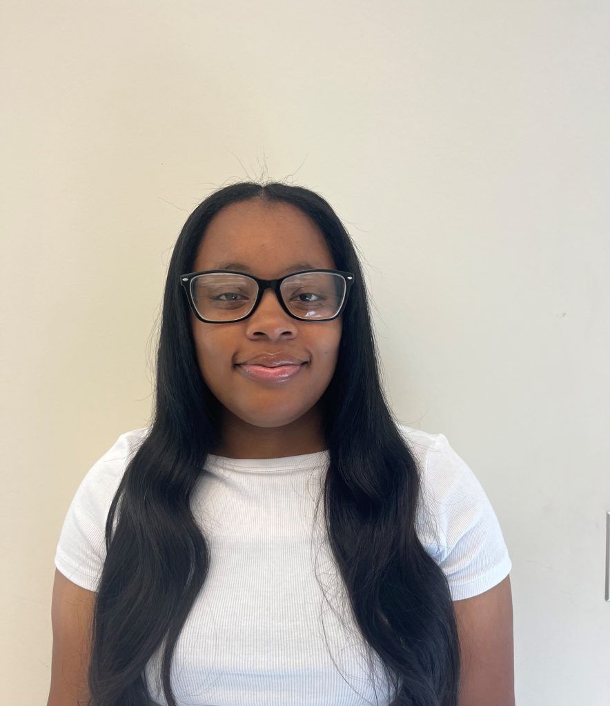 Headshot of Amirah Rice indoors against a blank wall