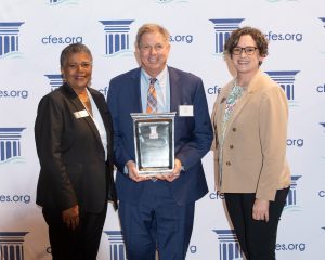 three people dressed in business attire holding a large award