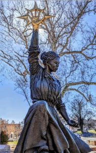 Metal statue of Harriet Tubman outside beside a tree