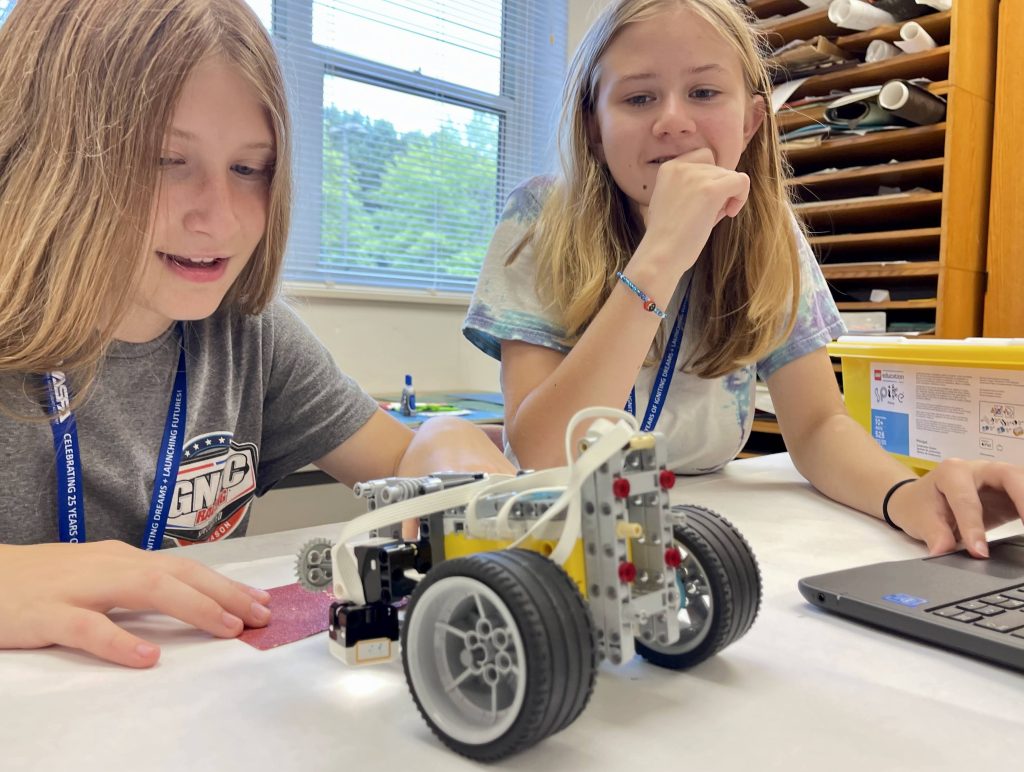 two young girls working together to build a model rover out of leggos