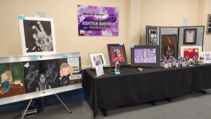 Large table with painting and drawings on display