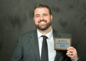 Headshot of a man in a suit holding an award