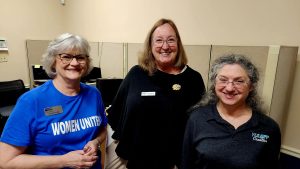 Three older women standing together at a networking event