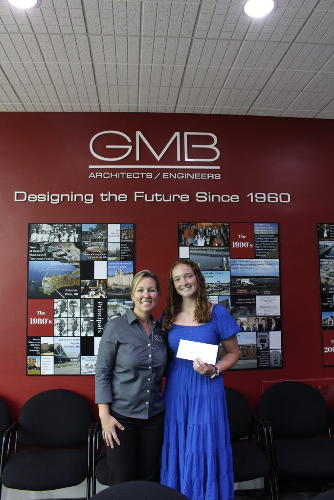 Two girls in business attire accepting a scholarship award