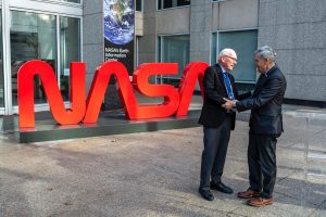 Two older gentleman shaking hands outside of a NASA building