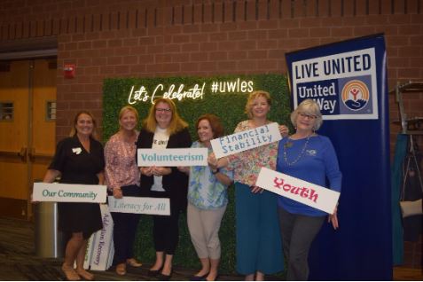 Group of women holding signs while posing in front of a back drop