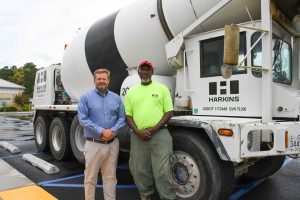 two men standing beside a cement truck