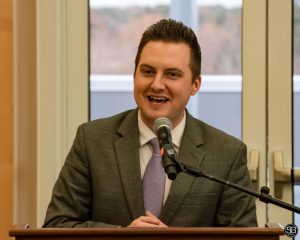 Man in a suit speaking into a microphone at a podium