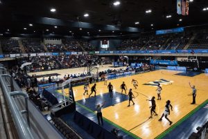 Players on the basketball court listening to the ref