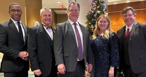 Five people dressed in business attire for a graduation ceremony