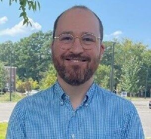 Headshot of a man with glasses standing outside