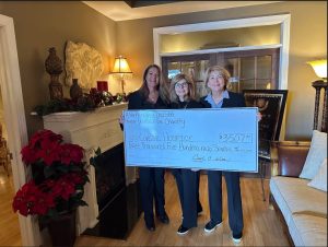 three women holding a large check for charity