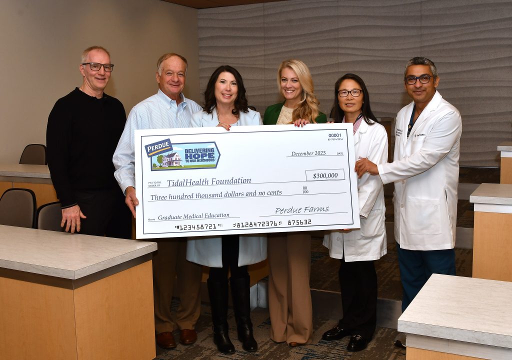 six people holding a large check