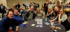 Male and female adults sitting around a round table at the Coast Chamber Mixer 2024