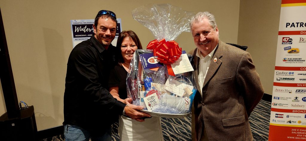 Three people holding a gift basket